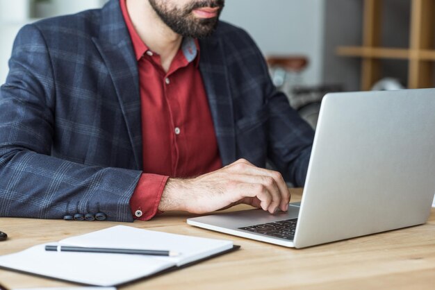 Foto captura recortada del hombre de negocios que trabaja con una computadora portátil en la oficina