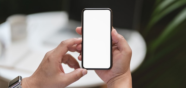 Captura recortada del hombre que sostiene el teléfono inteligente con fondo de trabajo al aire libre