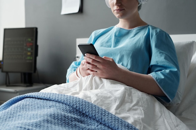 Captura recortada de una joven paciente en recuperación con un teléfono inteligente