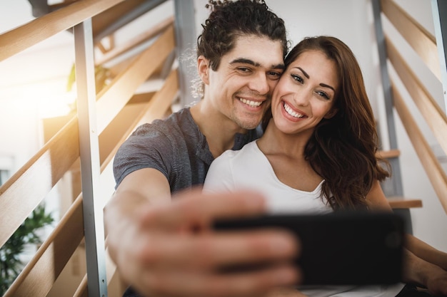 Captura recortada de una joven pareja afectuosa que se toma selfies mientras se muda de casa.