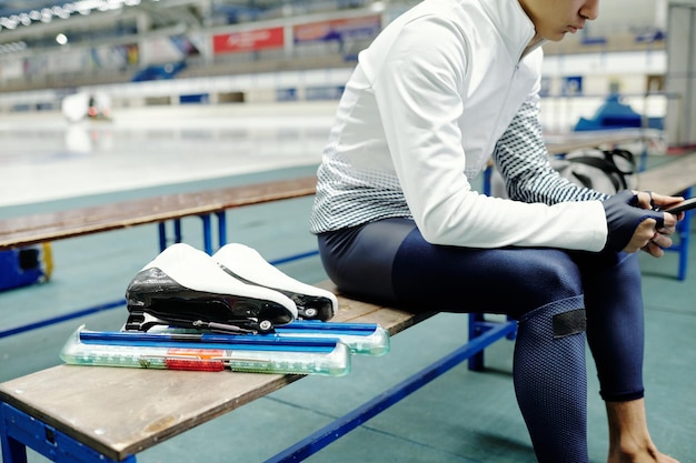 Captura recortada de un joven patinador sobre hielo en uniforme deportivo sentado en un banco