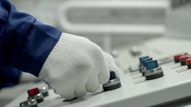 Captura recortada de la mano del operador de la máquina enciende el panel de control de la máquina industrial