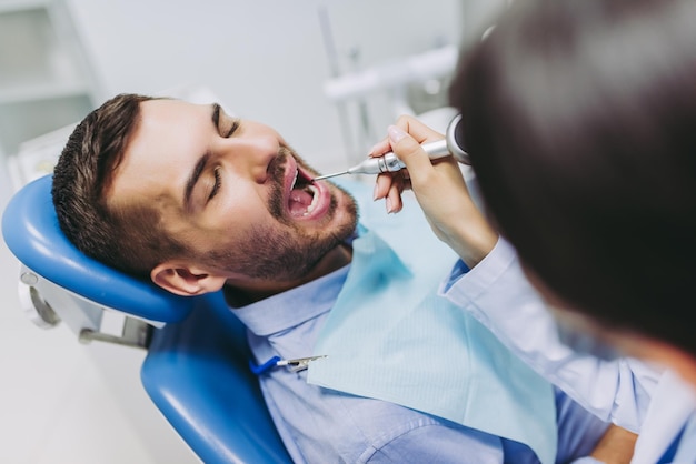 Foto captura recortada del médico que trata los dientes del paciente en la clínica dental moderna