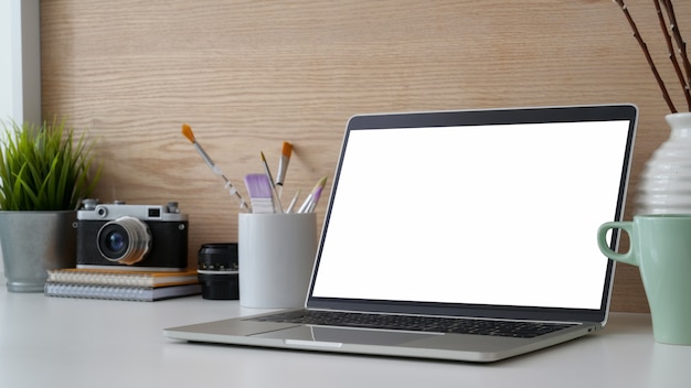 Foto captura recortada del moderno espacio de trabajo con un portátil con pantalla en blanco