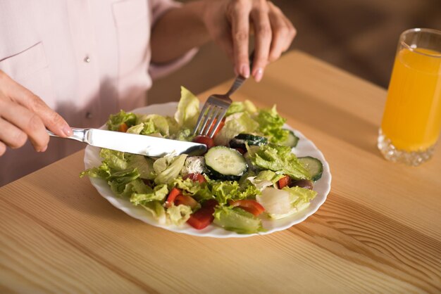 Captura recortada de mujer comiendo ensalada fresca en el café