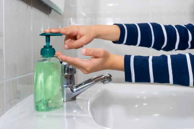 Captura recortada de un niño irreconocible poniéndose jabón en las manos para lavarse en casa
