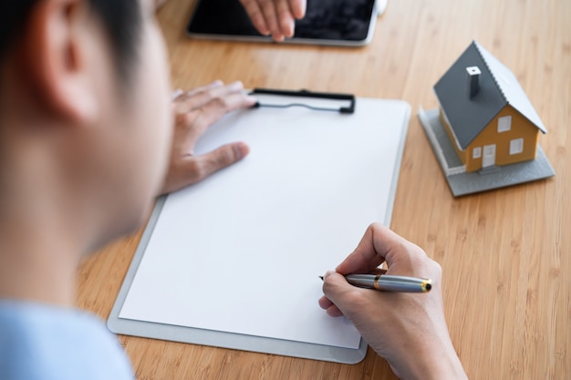 Foto captura recortada del propietario firmando un contrato de préstamo hipotecario en la oficina de la agencia inmobiliaria.