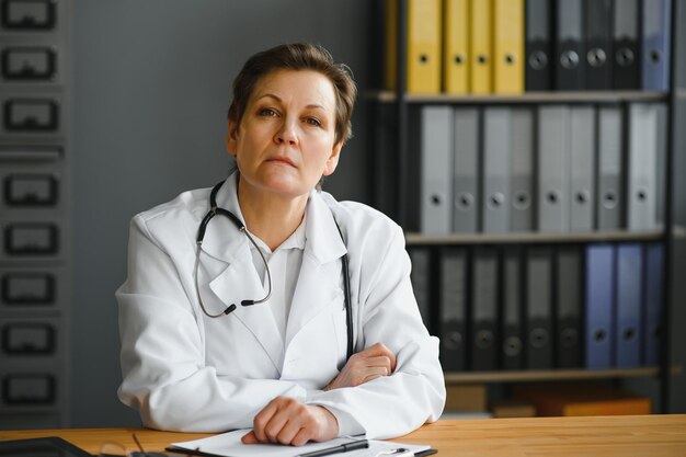 Captura de retrato de una doctora de mediana edad sentada en el escritorio y trabajando en la oficina