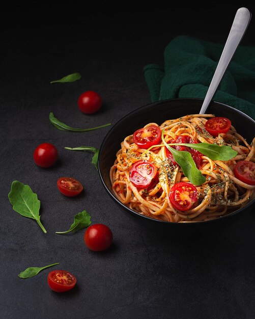 Captura vertical de massas deliciosas com tomate cereja em fundo preto