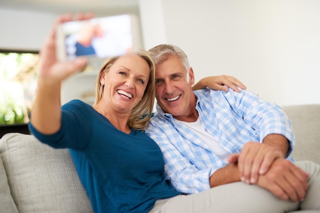 Capturando a beleza do amor Foto recortada de um casal maduro tirando uma selfie juntos em casa