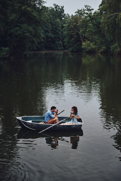 Capturando la belleza. Vista superior del joven fotografiando a su hermosa novia mientras disfruta de una cita romántica en el lago