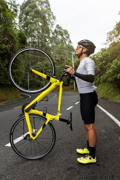 Capturando el momento en que un ciclista sonriente posa con el neumático trasero de una bicicleta de carretera