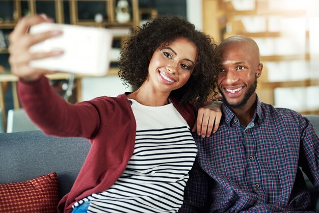 Capturar tiempo de calidad con un selfie Foto de una joven pareja feliz tomándose selfies juntos en casa