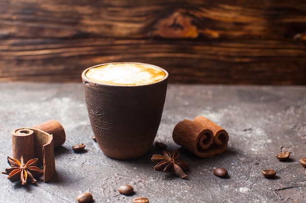 Capuccino en taza de barro artesanal con especias de canela y anís