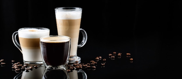 Capuchino, americano y latte macchiato con café sobre fondo oscuro