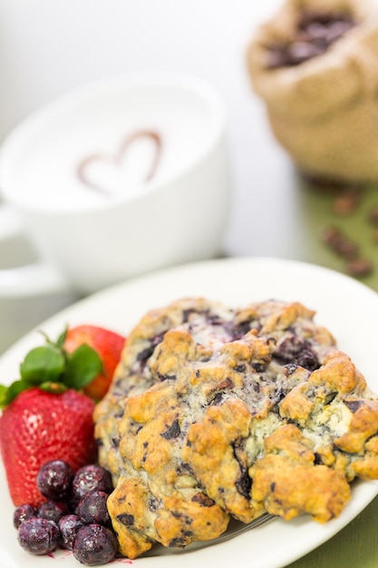 Capuchino con bollo de arándanos frescos para el desayuno.