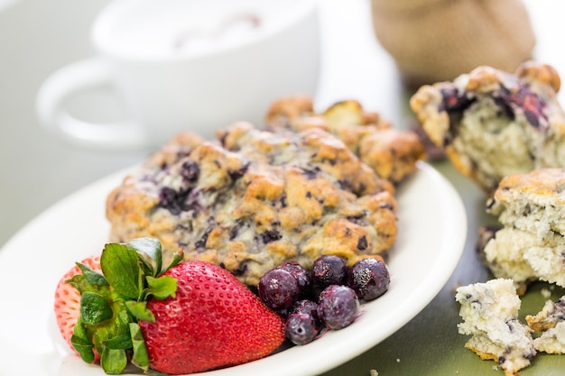 Capuchino con bollo de arándanos frescos para el desayuno.