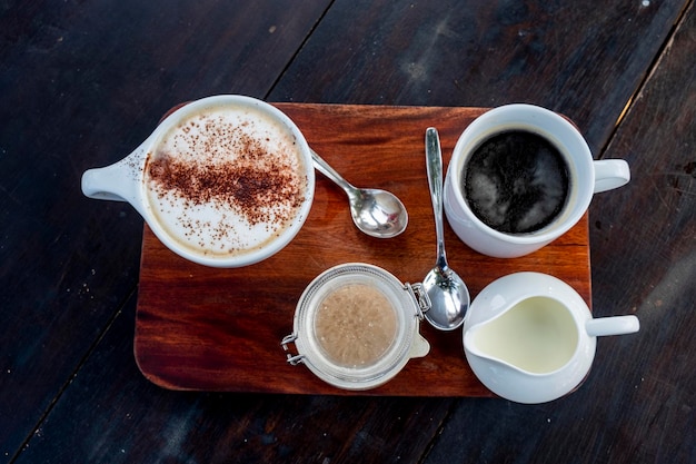 Capuchino y café americano con leche en una mesa de madera