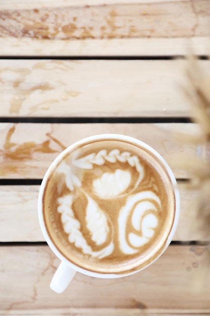 Capuchino con café Latte art hecho con leche en la mesa de madera de la cafetería