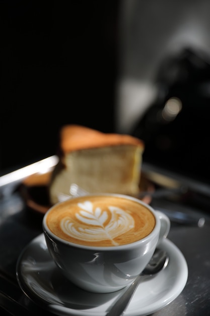 Capuchino caliente o café Latte art hecho con leche en la mesa de madera en la cafetería.