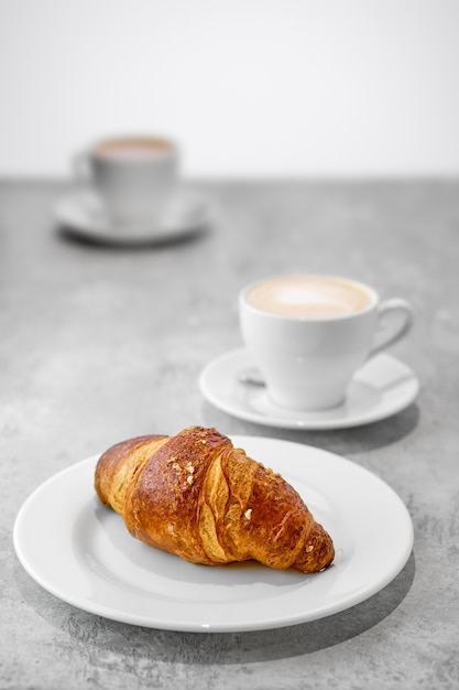 Capuchino y croissant en una mesa