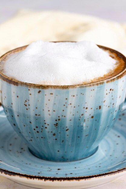 Capuchino de espuma sobre un fondo de madera blanca