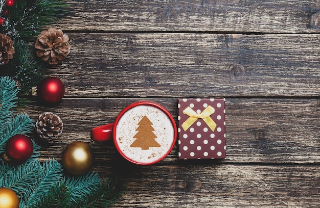 Capuchino con forma del árbol de navidad y regalo en la tabla de madera.