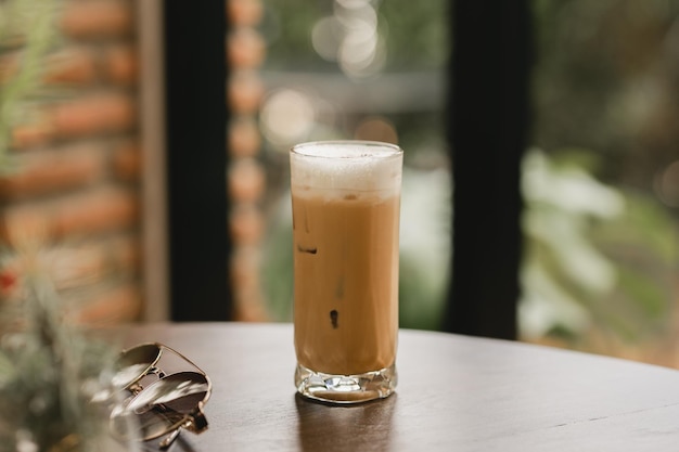 Capuchino helado en un vaso sobre una mesa de madera en el café