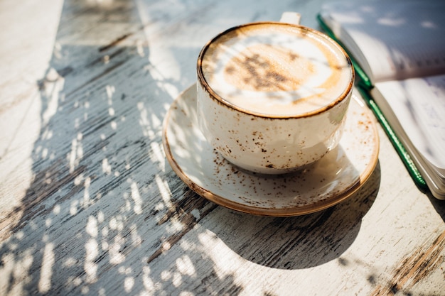 Capuchino en una hermosa taza de cerámica está sobre la mesa de un café. Delicioso desayuno aromático.