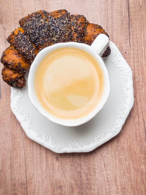 Capuchino con hermoso arte latte y croissant sobre fondo de madera en la mesa Desayuno perfecto por la mañana