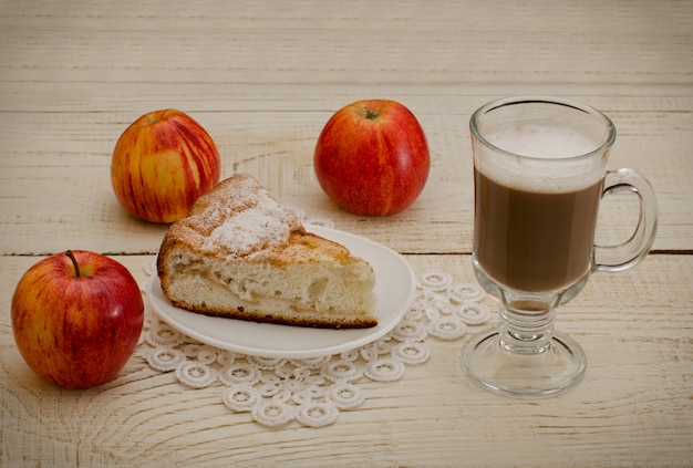Capuchino, manzanas maduras y tarta de manzana sobre una mesa de madera blanca
