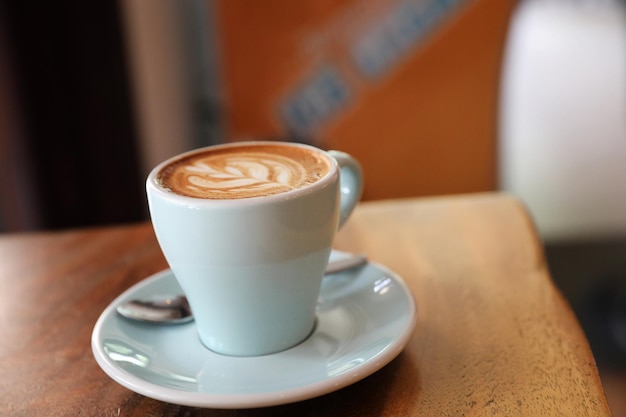 Capuchino o café Latte art hecho con leche en la mesa de madera de la cafetería