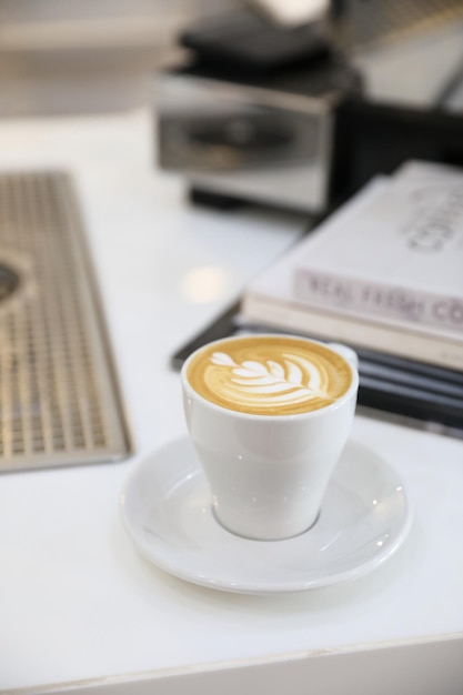 Capuchino o café Latte art hecho con leche en la mesa de madera de la cafetería