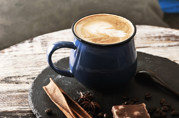 Capuchino en una taza con espuma de leche y canela y chocolate.