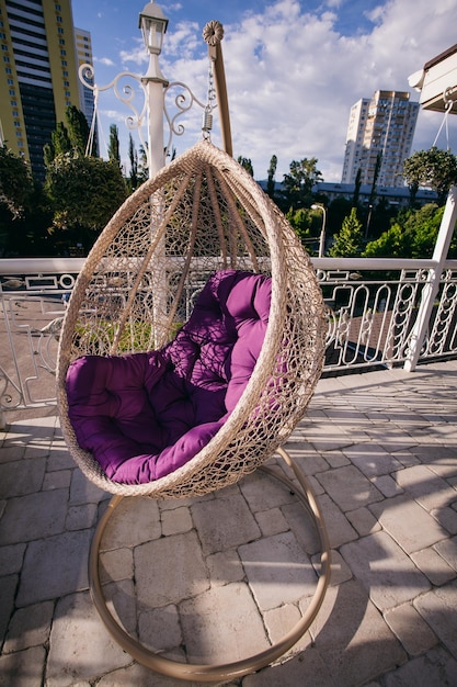 capullo de silla colgante con un cojín morado en la terraza de verano del restaurante