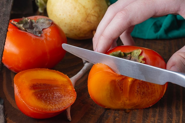 Caqui doce fatiado em mesa de madeira escura em luz escuraFrutas tradicionais sazonais