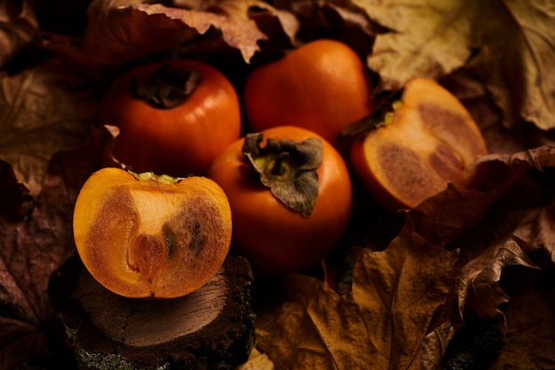 Caqui fatiado fresco frutas em folhas de outono laranja na madeira