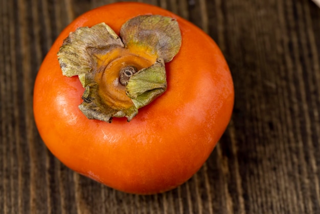 Foto caqui laranja maduro inteiro sobre a mesa frutas de caqui laranja não lavadas antes de cozinhar