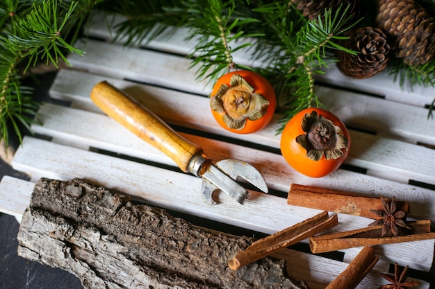 Caquis en una bandeja de madera y árbol de Navidad