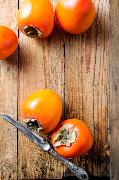 Caquis de laranja maduros sobre uma velha mesa de madeira