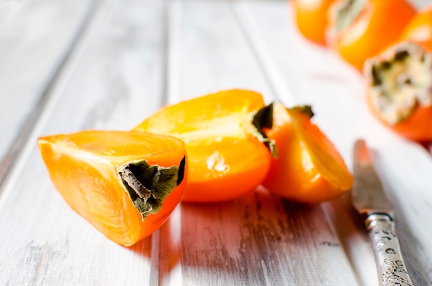 Caquis de laranja maduros sobre uma velha mesa de madeira