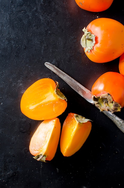 Foto caquis de naranja maduros sobre el negro.