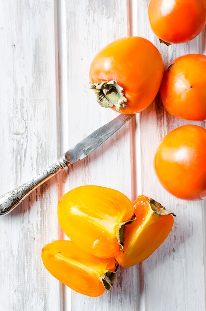 Caquis naranjas maduros en una vieja mesa de madera