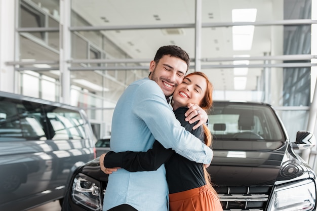 Foto cara abraça a namorada em uma concessionária de carros