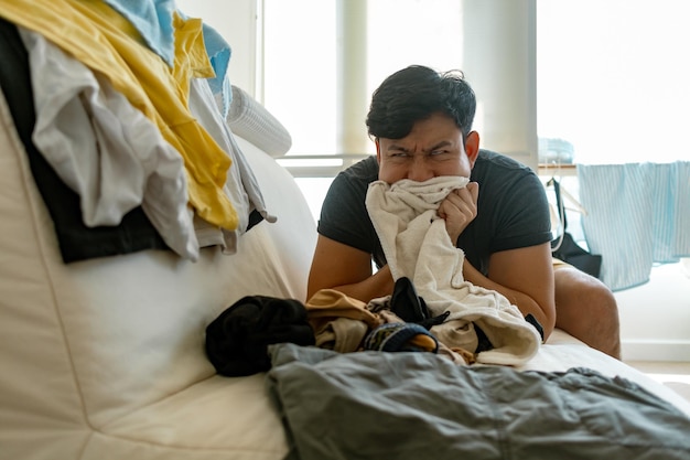 Foto cara aburrida hombre asiático recogiendo y arreglando ropa concepto de las tareas domésticas
