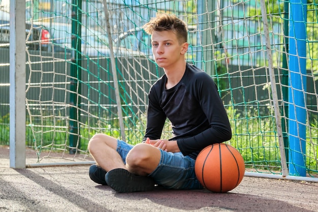 Cara adolescente com bola, fundo de quadra da cidade de basquete ao ar livre. estilo de vida saudável de esportes ativos de adolescentes na cidade