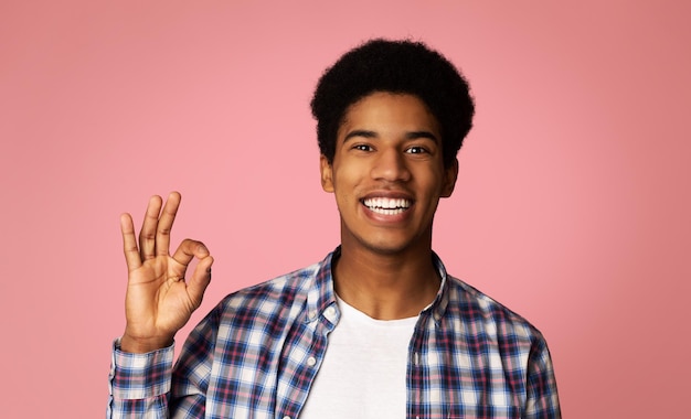 Cara afro feliz gesticulando sinal de OK e sorrindo