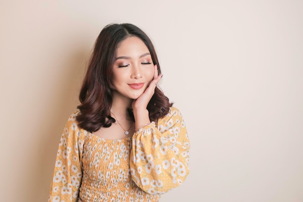 Una cara alegre de belleza de una joven modelo asiática con un top floral amarillo Cuidado de la piel belleza tratamiento facial spa concepto de salud femenina