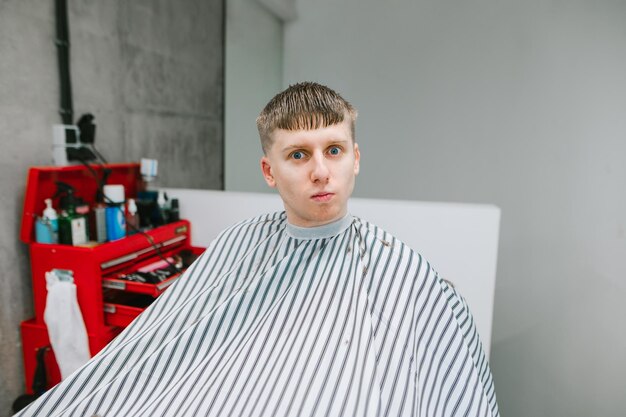 Cara alegre corta o cabelo em uma barbearia