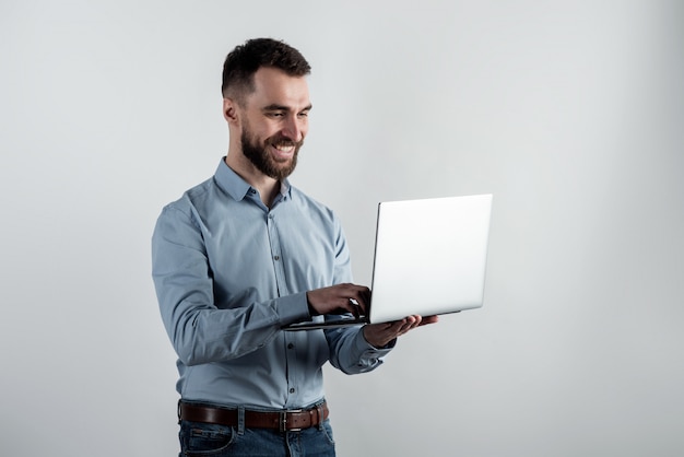 Foto cara alegre de camisa azul fica segurando um laptop aberto